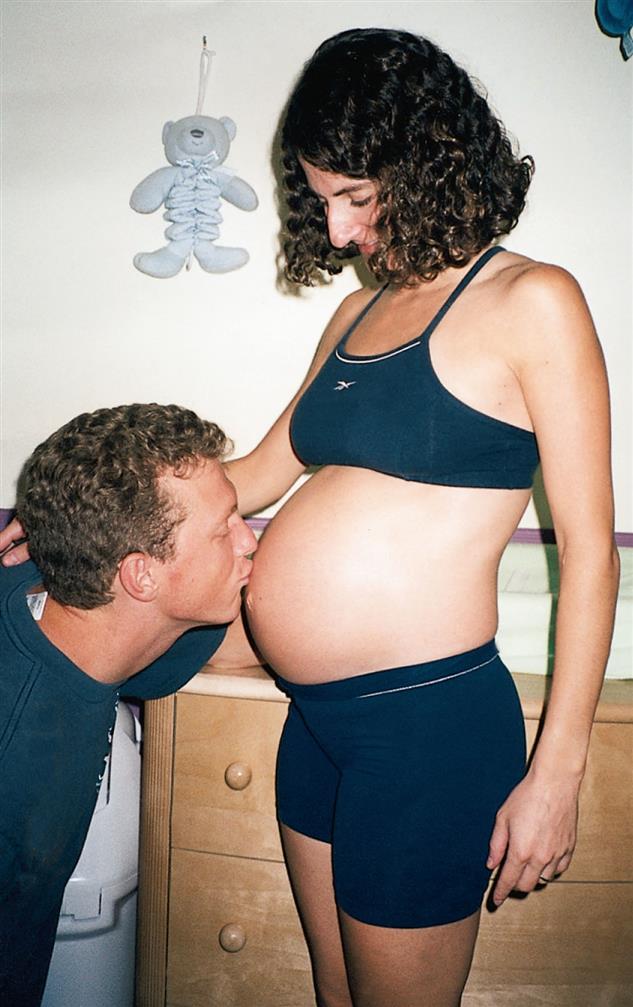A man kissing the baby bump of a pregnant woman.